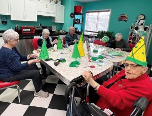 Group of seniors in 50s sensory room making caps craft for St. Patrick's day