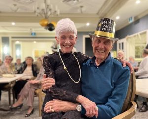 Older couple on new year's eve, woman with short grey hair sitting on lap of distinguished older man
