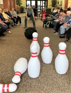 Senior throwing a giant inflatable bowling ball at pins