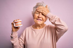 Oral Health Tips for Seniors and Caregivers - All Seniors Care Older woman with short hair holding dentures