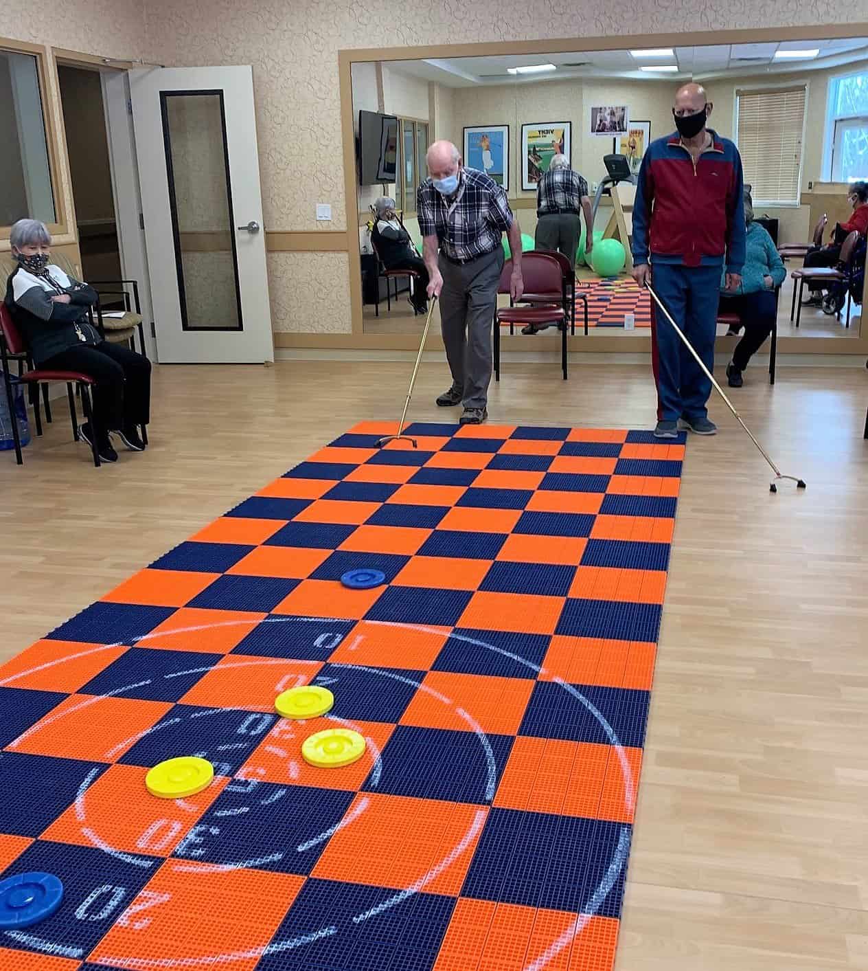 Ted Lasso inspire les aînés canadiens à "Croire". - All Seniors Care Senior men playing shuffleboard at a retirement residence